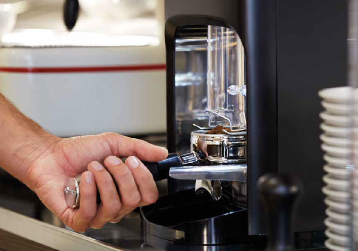 Close-up of La Cimbali Elective Manual Tamper grinder dispensing coffee grounds into a portafilter - La Cimbali Elective Manual Tamper Grinder – Precision Grinding for Perfect Espresso - Close-up of the Elective Manual Tamper grinder by La Cimbali delivering precise coffee doses into a portafilter — perfect for cafés and professional baristas.